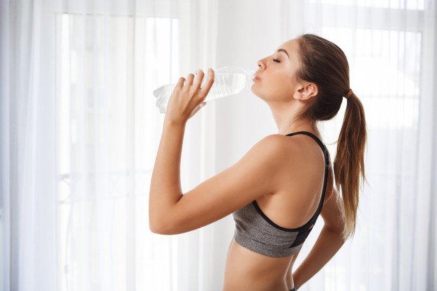 chica-hermosa-fitness-bebiendo-agua-botella-plastico_176420-6080